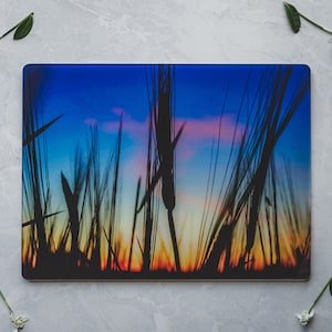 May include: A glass chopping board featuring a photograph of a field of tall grass silhouetted against a colourful sunset sky. The sky is a gradient of blue, pink, orange, and yellow.