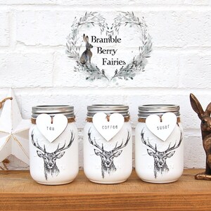 May include: Three white mason jars with silver lids, each featuring a deer graphic and a heart-shaped tag labelled "Tea", "Coffee", and "Sugar". A bronze rabbit statue and a white star decoration are also present.