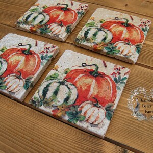 May include: Set of four square ceramic coasters with an autumnal theme. Each coaster features a different arrangement of pumpkins, gourds, and autumn foliage in shades of orange, green, and white. The coasters are decorated with a rustic, vintage-inspired design.