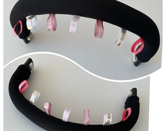Puede incluir: Manillar de cochecito negro con lazos de cinta rosa, blanca y dorada.