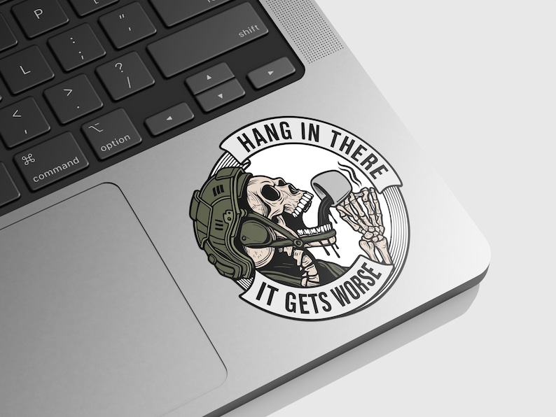 May include: A sticker featuring a skeleton wearing a helmet and drinking from a mug. The sticker has the text "HANG IN THERE" above the skeleton and "IT GETS WORSE" below. The sticker is on a laptop.