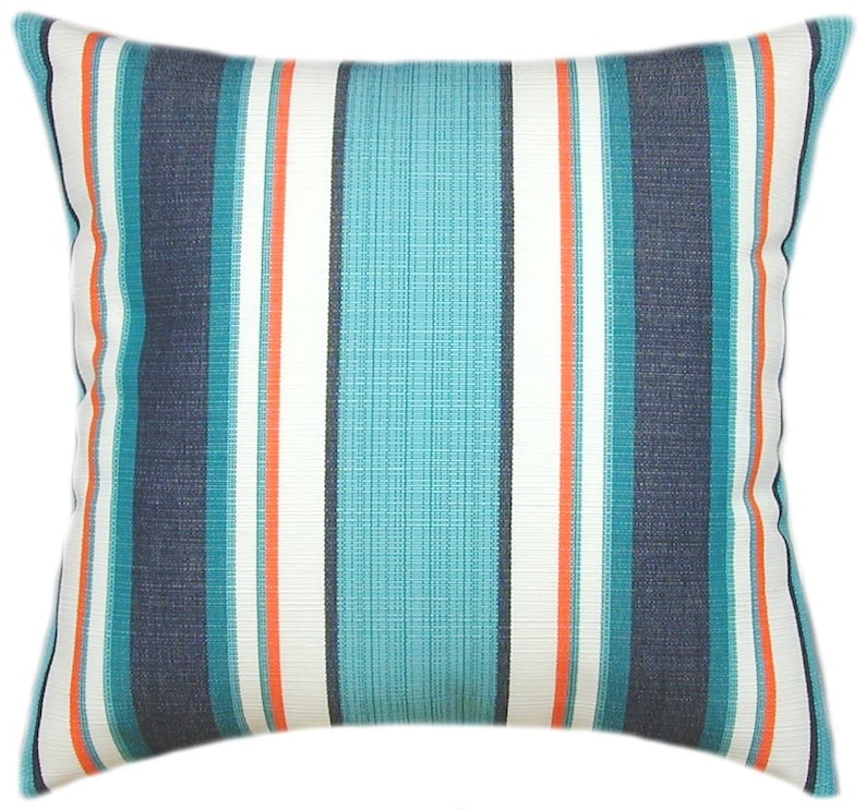 Puede incluir: Una almohada de rayas con rayas de color azul verdoso, azul marino, blanco y naranja. La almohada est&aacute; hecha de una tela suave y texturizada.