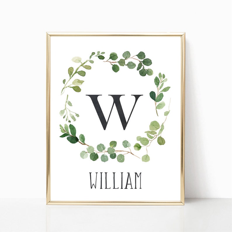 May include: A printable art print with a gold frame featuring a watercolor wreath of green leaves with a black letter W in the center and the name William below.