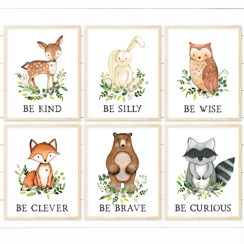 May include: Set of six watercolor illustrations featuring woodland animals with inspirational messages. The illustrations include a deer, rabbit, owl, fox, bear, and raccoon. Each animal is surrounded by green leaves and flowers. The messages are "Be Kind", "Be Silly", "Be Wise", "Be Clever", "Be Brave", and "Be Curious".