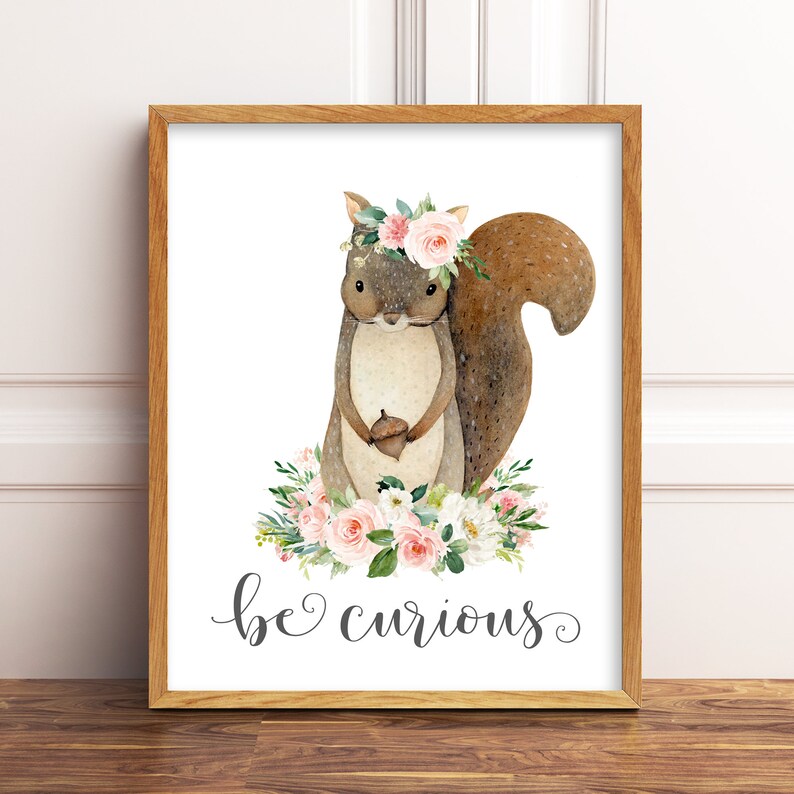 May include: A watercolor illustration of a brown squirrel wearing a pink flower crown and holding an acorn. The squirrel is surrounded by pink and white flowers and green leaves. The text "be curious" is written below the squirrel.