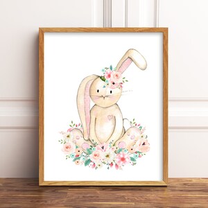 May include: A watercolor illustration of a beige bunny wearing a pink flower crown and sitting on a bed of pink, white, and green flowers.