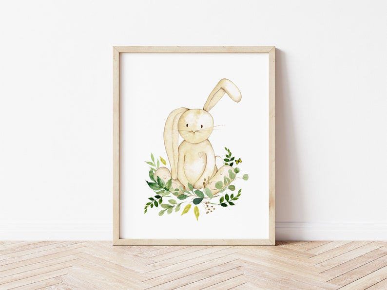 K&ouml;nnte beinhalten: Eine Aquarell-Illustration eines beigefarbenen Kaninchens, das in einem Bett aus gr&uuml;nen und gelben Bl&auml;ttern sitzt. Das Kaninchen hat ein langes, schlaffes Ohr und einen s&uuml;&szlig;en Ausdruck.