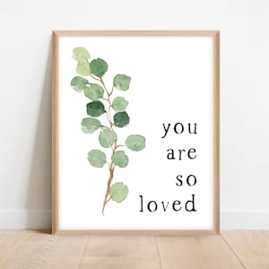 Könnte beinhalten: Ein gerahmter Druck mit einer Aquarell-Illustration eines Eukalyptus-Zweigs und dem Text "you are so loved".