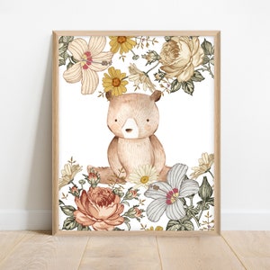 Puede incluir: Una ilustración de acuarela de un oso marrón sentado en un campo de flores. Las flores son en tonos de amarillo, rosa y blanco. El oso está mirando al espectador.