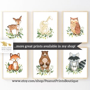 May include: Set of six watercolor animal prints featuring a deer, rabbit, owl, fox, bear, and raccoon. Each animal is surrounded by green foliage. The prints are perfect for a nursery or child's room.