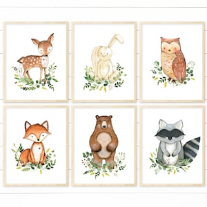 May include: Set of six watercolour illustrations featuring woodland animals. The animals include a deer, rabbit, owl, fox, bear, and raccoon. Each animal is surrounded by green leaves and flowers.