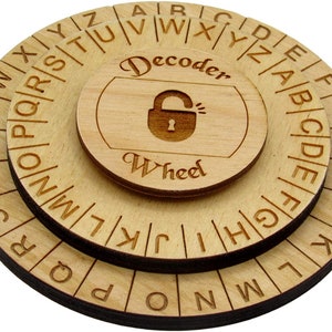 Op de afbeelding: Een houten decoderwiel met drie draaiende schijven. Elke schijf heeft het alfabet erop gedrukt. De middelste schijf heeft een hangslotpictogram en de tekst "Decoder Wheel".