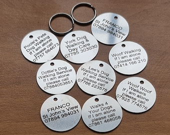 May include: A collection of eight round silver dog tags with black text. Each tag has a different message and phone number for contacting the owner if the dog is found alone. The messages include "Poole's Pets Dog Walking", "York Dog Walking & Day Care", "Dottie's Dog Walking Service", "Woof Walking", "Lee's Dog Walking Service", "Woof Woof Walkers", "FRANCO St John's View", and "Walks 4 Your Dogs".