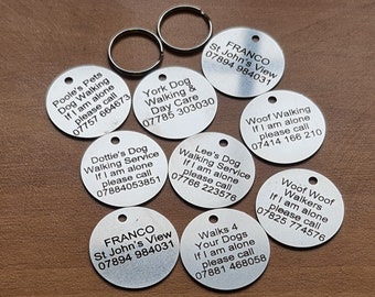 May include: A collection of eight round silver dog tags with black text. Each tag has a different message and phone number for contacting the owner if the dog is found alone. The messages include "Poole's Pets Dog Walking", "York Dog Walking & Day Care", "Dottie's Dog Walking Service", "Woof Walking", "Lee's Dog Walking Service", "Woof Woof Walkers", "FRANCO St John's View", and "Walks 4 Your Dogs".