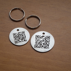 May include: Two silver keychains with round metal tags featuring black and white QR codes.