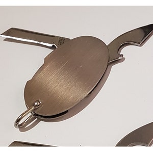 Peut inclure: Un porte-clés multi-outils argenté avec un ouvre-bouteille, un petit couteau et un anneau.