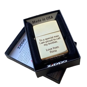 Puede incluir: Un encendedor Zippo dorado en una caja negra. El encendedor tiene un mensaje grabado que dice "To a special man I am proud to call my brother. Love from Fiona". La caja est&aacute; etiquetada con "Made in USA".