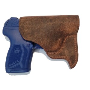 May include: A brown leather holster for a blue Ruger pistol.