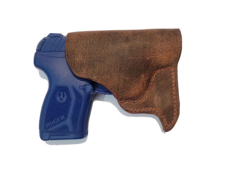 May include: A brown leather holster for a blue Ruger pistol.