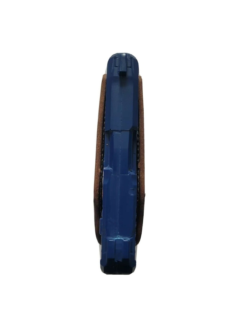 Puede incluir: Una pistola azul en una funda de cuero marr&oacute;n. El arma es de color azul s&oacute;lido y est&aacute; parcialmente encerrada en la funda. La funda es de color marr&oacute;n oscuro y parece ser de cuero.