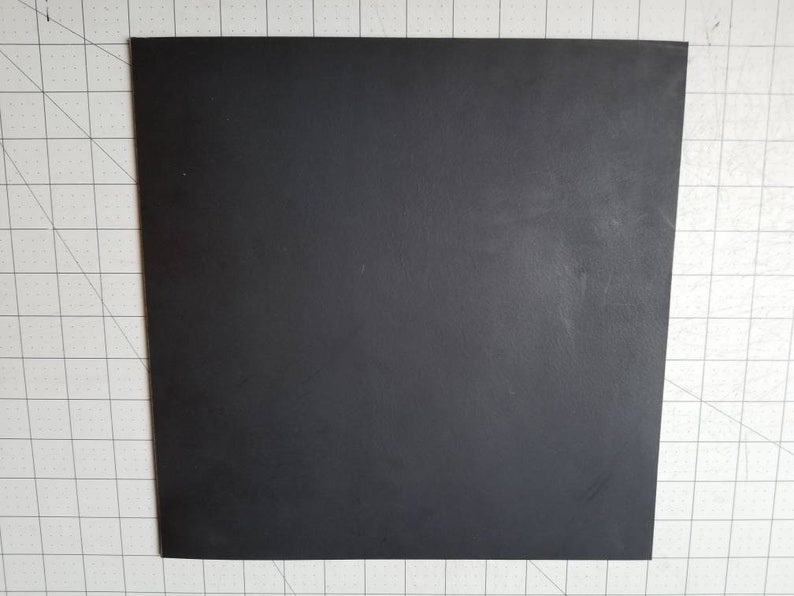 Op de afbeelding: Een zwart vierkant stuk materiaal. Het lijkt op een vel rubber of plastic.
