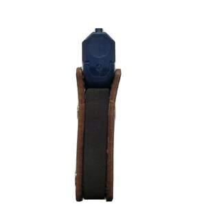 Puede incluir: Una pistola azul es parcialmente visible, dentro de una funda de cuero marr&oacute;n. La funda tiene un inserto rectangular oscuro, probablemente para mayor comodidad o protecci&oacute;n. La imagen est&aacute; sobre un fondo blanco.