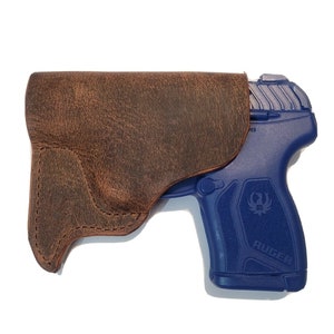 May include: A brown leather holster for a blue Ruger pistol.