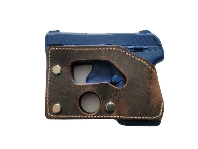 May include: A brown leather holster with a stitched edge and silver rivets. The holster is designed to hold a small, blue handgun.