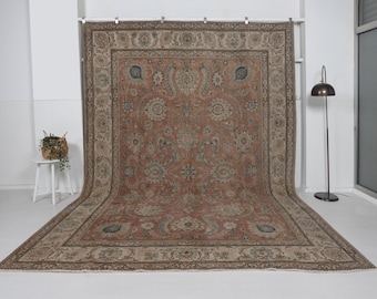 Puede incluir: Una alfombra rectangular grande con un intrincado diseño floral en tonos óxido, beige y azul. La alfombra presenta un borde detallado y un diseño de medallón central. La alfombra se exhibe en interiores, mostrando su tamaño y diseño.