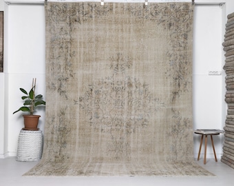Könnte beinhalten: Ein Vintage-Teppich mit einem verblassten Blumenmuster in Beige- und Grautönen. Der Teppich hat einen abgenutzten Look und ist perfekt, um jedem Raum einen Hauch von rustikalem Charme zu verleihen.