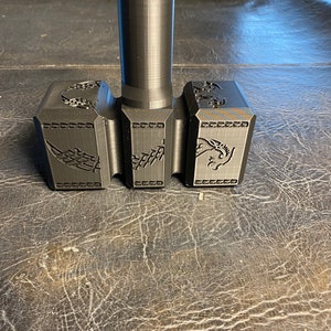 May include: A black 3D printed hammer with a cylindrical handle and a three-section head. Each section of the head features a detailed design.