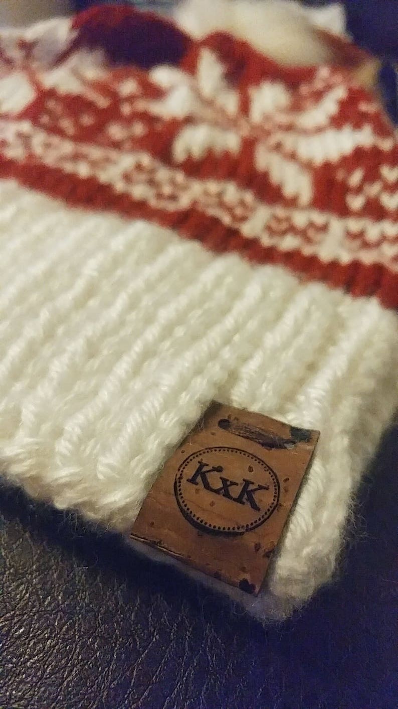 May include: White and red knitted hat with a brown leather tag that says "K.K.K."