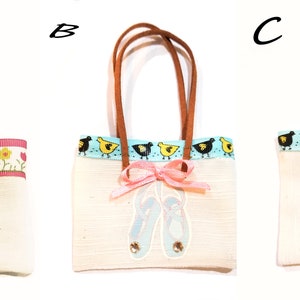 May include: Three small tote bags with different designs. The first bag has a pink flower with yellow leaves. The second bag has a blue and white ribbon with a row of black and yellow birds. The third bag has a pink ribbon with a pair of pink ballet shoes.