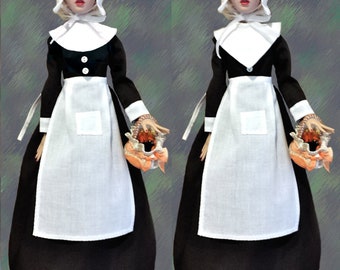 May include: Two dolls dressed in black and white pilgrim outfits with white bonnets and carrying baskets. The dolls are standing on a textured background.