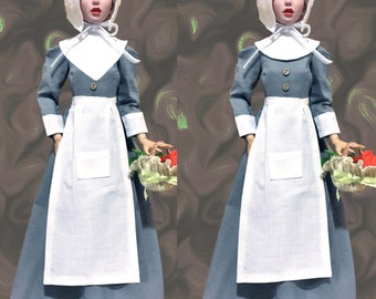 May include: Two dolls wearing blue and white dresses with white bonnets and aprons. Each doll is holding a basket of flowers.