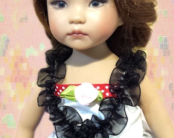 May include: A porcelain doll with brown hair wearing a white dress with black lace trim and a red and white polka dot bow headband.