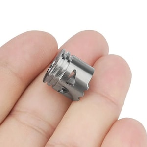 May include: A silver metal coil for a vape device. The coil has a cylindrical shape with a series of holes and a small opening on the side.