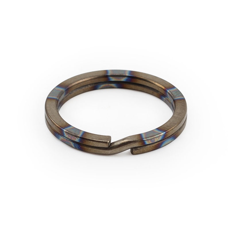 Op de afbeelding: Een dubbele titanium sleutelhanger met een blauwe en bruine iriserende afwerking.