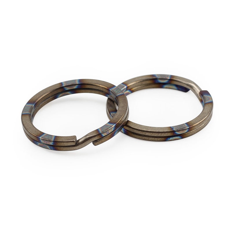 Op de afbeelding: Twee titanium sleutelringen met een blauw-bruine warmtebehandelde afwerking.
