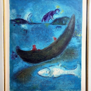 Pode incluir: Uma impressão emoldurada de uma pintura de Marc Chagall, apresentando um barco escuro com figuras vermelhas, um peixe branco e um fundo azul. Uma figura roxa está em pé sobre uma rocha. A obra de arte é assinada e numerada.