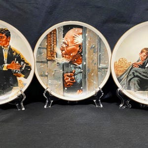 Puede incluir: Tres platos de cerámica decorativos con ilustraciones de Norman Rockwell. El primer plato muestra una pareja joven caminando juntos, el segundo plato muestra a un hombre mirando por una ventana y el tercer plato muestra a un hombre con dos niños.