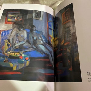 May include: A painting of two nude figures reclining on a blue couch. The figures are painted in a stylized, abstract style with muted colors. The painting is set in a room with a window and other furniture.
