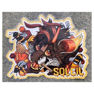 Op de afbeelding: Een kleurrijke illustratie van een harige dier met een rood, oranje en bruine vacht, die een stok honing vasthoudt. Het dier wordt omringd door bijen en honingraatpatronen. Het woord "SOLEIL" staat in druipende gele verf onderaan de afbeelding.