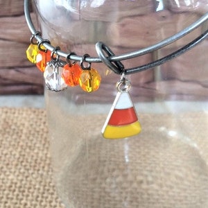 Può includere: Un braccialetto con ciondoli in argento con perline di vetro arancioni e gialle, un ciondolo di cristallo trasparente e un ciondolo a forma di mais caramellato.