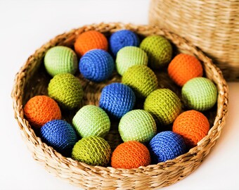 May include: A wicker basket filled with colourful crocheted balls. The balls are in shades of green, blue, orange, and red.