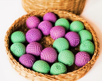 May include: A wicker basket filled with crocheted balls in shades of green and purple. The balls are arranged in a circular pattern, creating a visually appealing display.