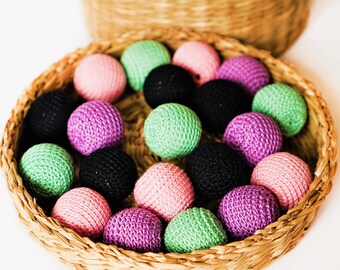 May include: A wicker basket filled with crocheted balls in various colours, including pink, green, purple, and black.