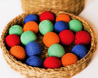 May include: A wicker basket filled with colourful crocheted balls. The balls are in shades of red, orange, green, blue, and yellow.