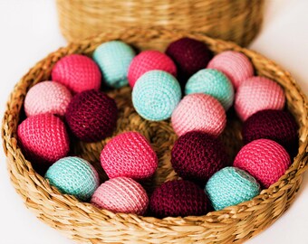 May include: A wicker basket filled with colourful crocheted balls. The balls are in shades of pink, red, blue, and purple.