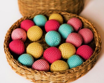 May include: A wicker basket filled with colourful crocheted balls. The balls are in shades of pink, yellow, blue, and green.